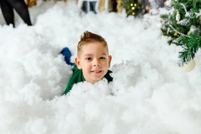 Bambino sorridente tra la neve finta, fotografia di Natale per bambini a Torino