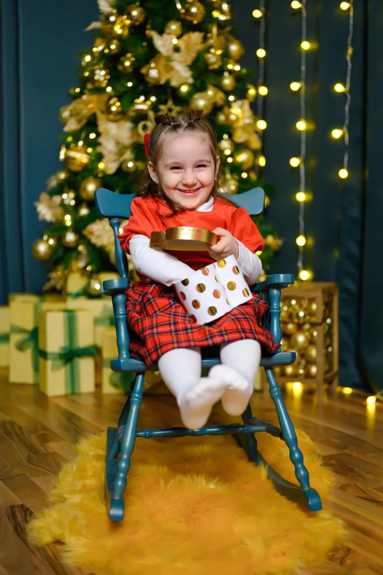 Bambina vestita di rosso tra luci dorate e regali, foto di Natale in studio a Venaria Reale
