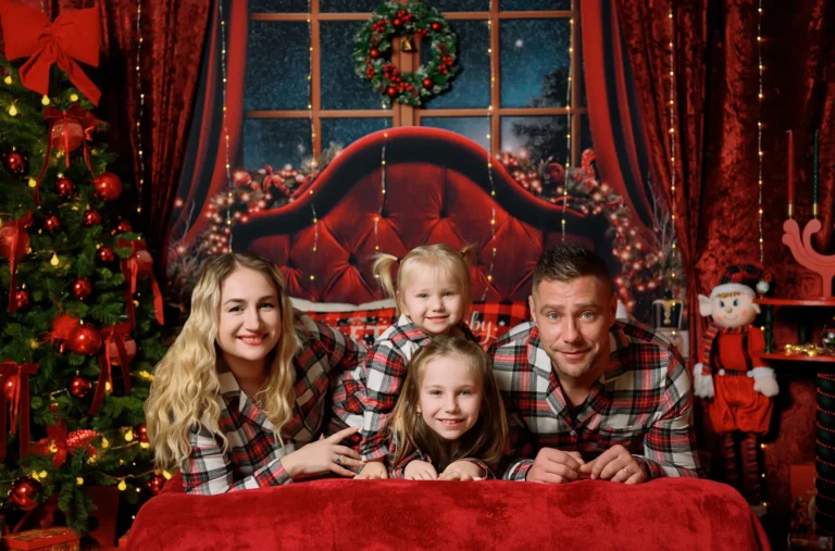 Famiglia in pigiami scozzesi rossi con due bambine, servizio fotografico di Natale in studio