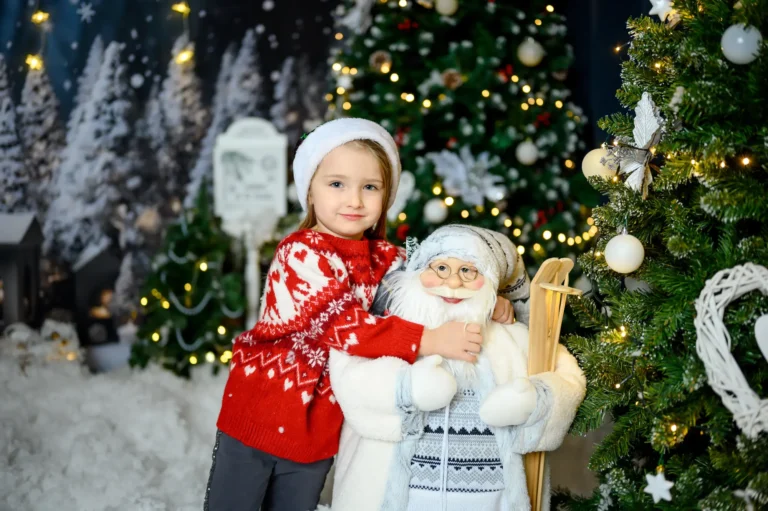 Bambina con cappello di Babbo Natale accanto a una statua di Babbo Natale, foto di Natale in studio