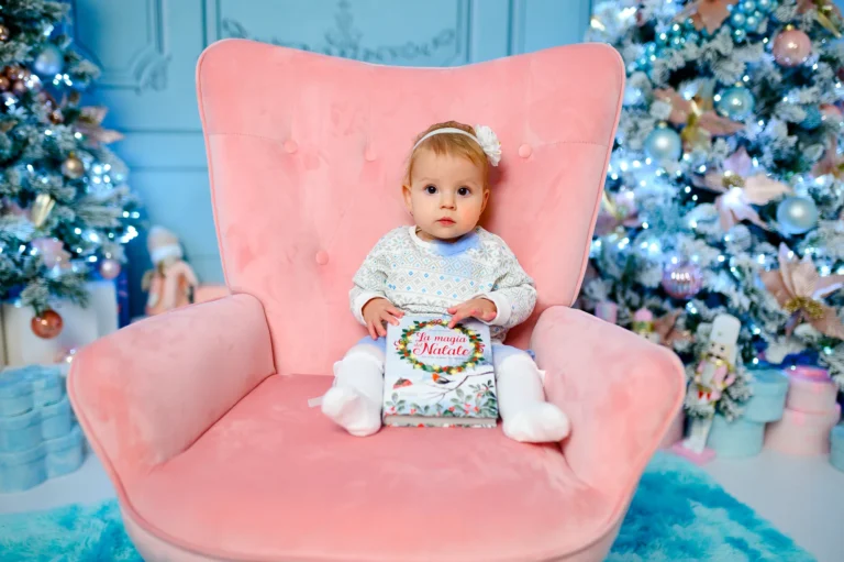 Bimba su una poltrona rosa accanto all’albero azzurro, foto di Natale in studio a Venaria Reale