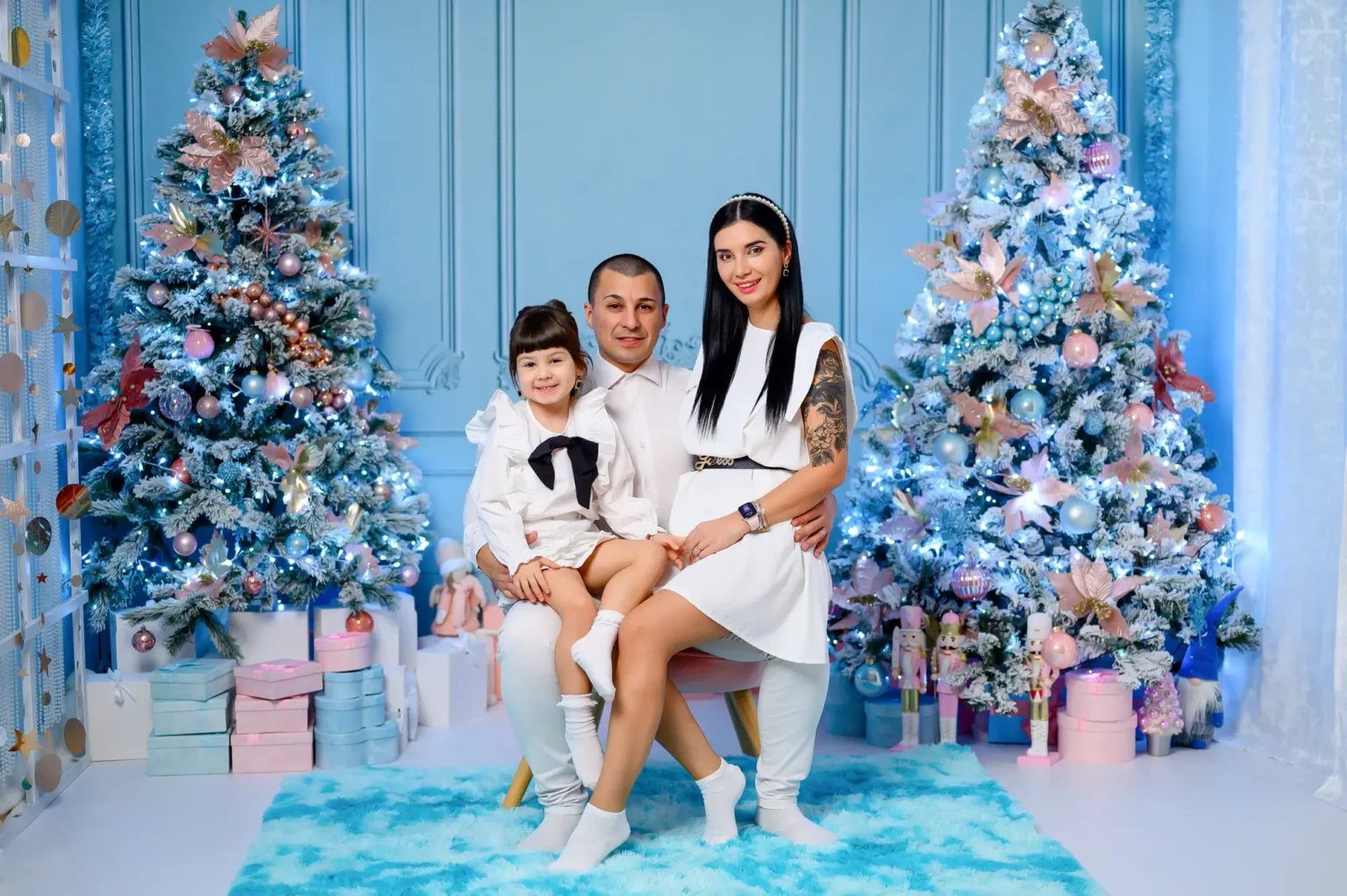 Famiglia vestita di bianco davanti a un albero di Natale azzurro, foto di Natale a Torino